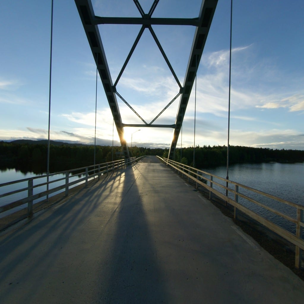 A bridge stretching over calm water toward the sunrise