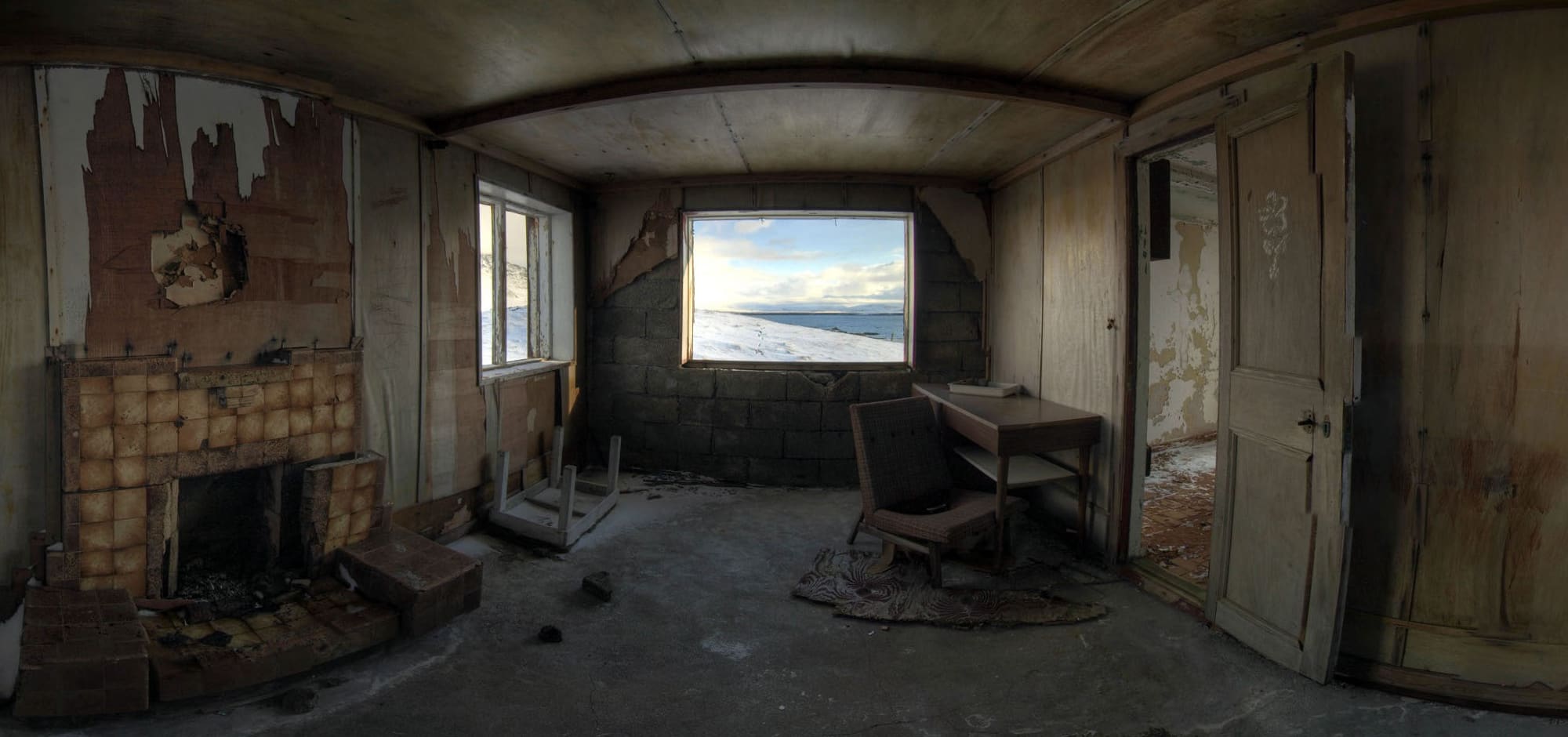 An old, abandoned office room with a single desk facing a window