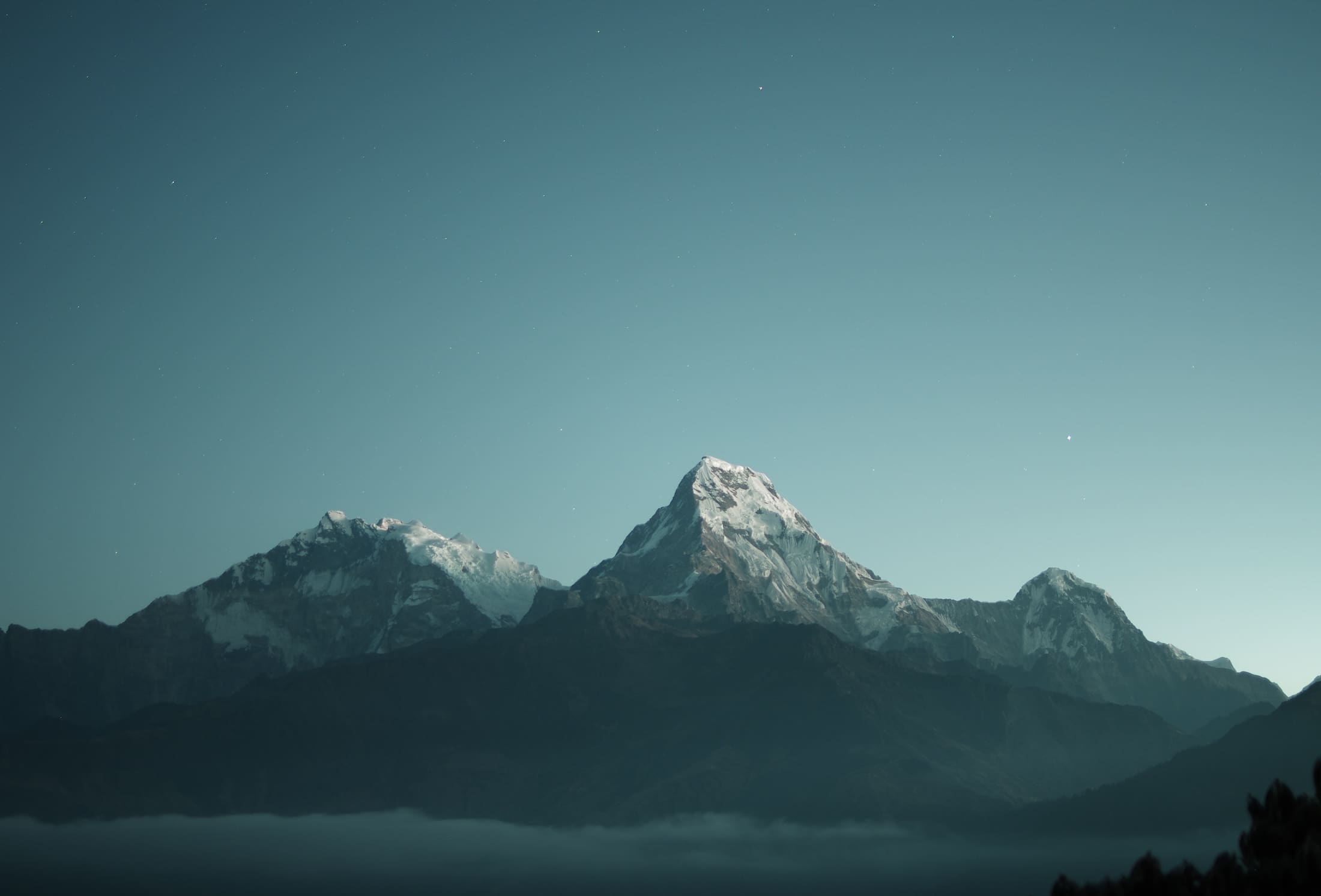 Snow-capped mountain peaks at dawn above a sea of clouds